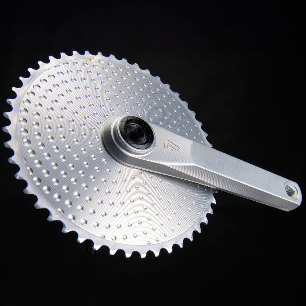 Silver ALUGEAR Vega AL road gravel crankset with round AERO Golf Ball chainring attached, drive side, dark background