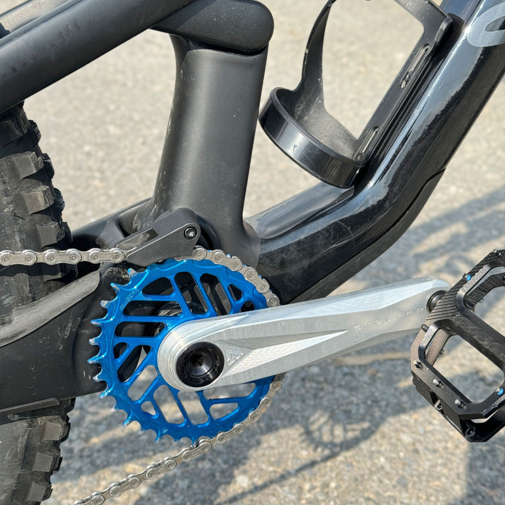 Srebrna korba ALUGEAR Stellar AL MTB z niebieską zębatką direct-mount zamontowana na rowerze, ujęcie z boku, lifestyle