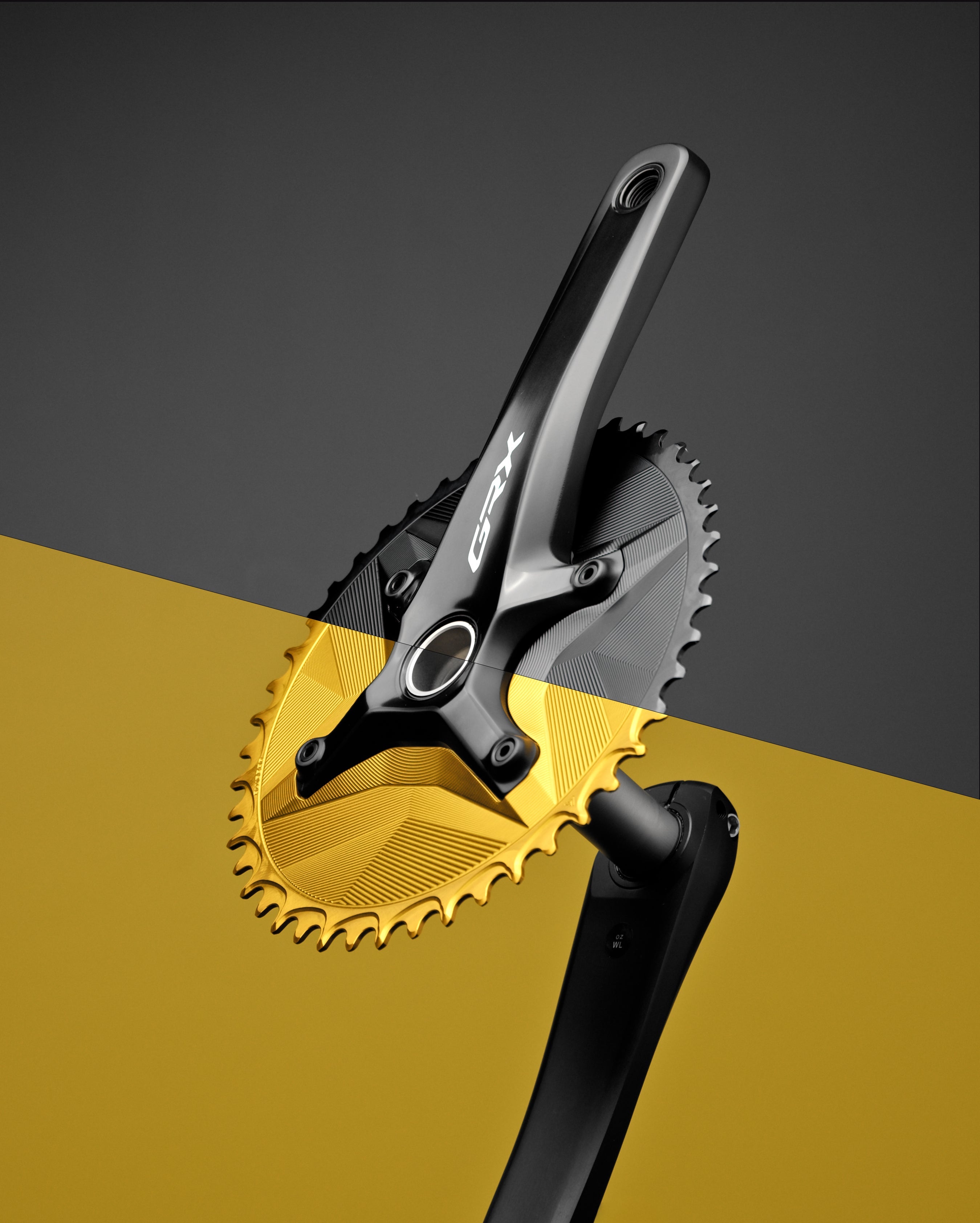 Gold ALUGEAR 1X narrow-wide chainring on Shimano GRX crank, styled product shot on gold and grey background