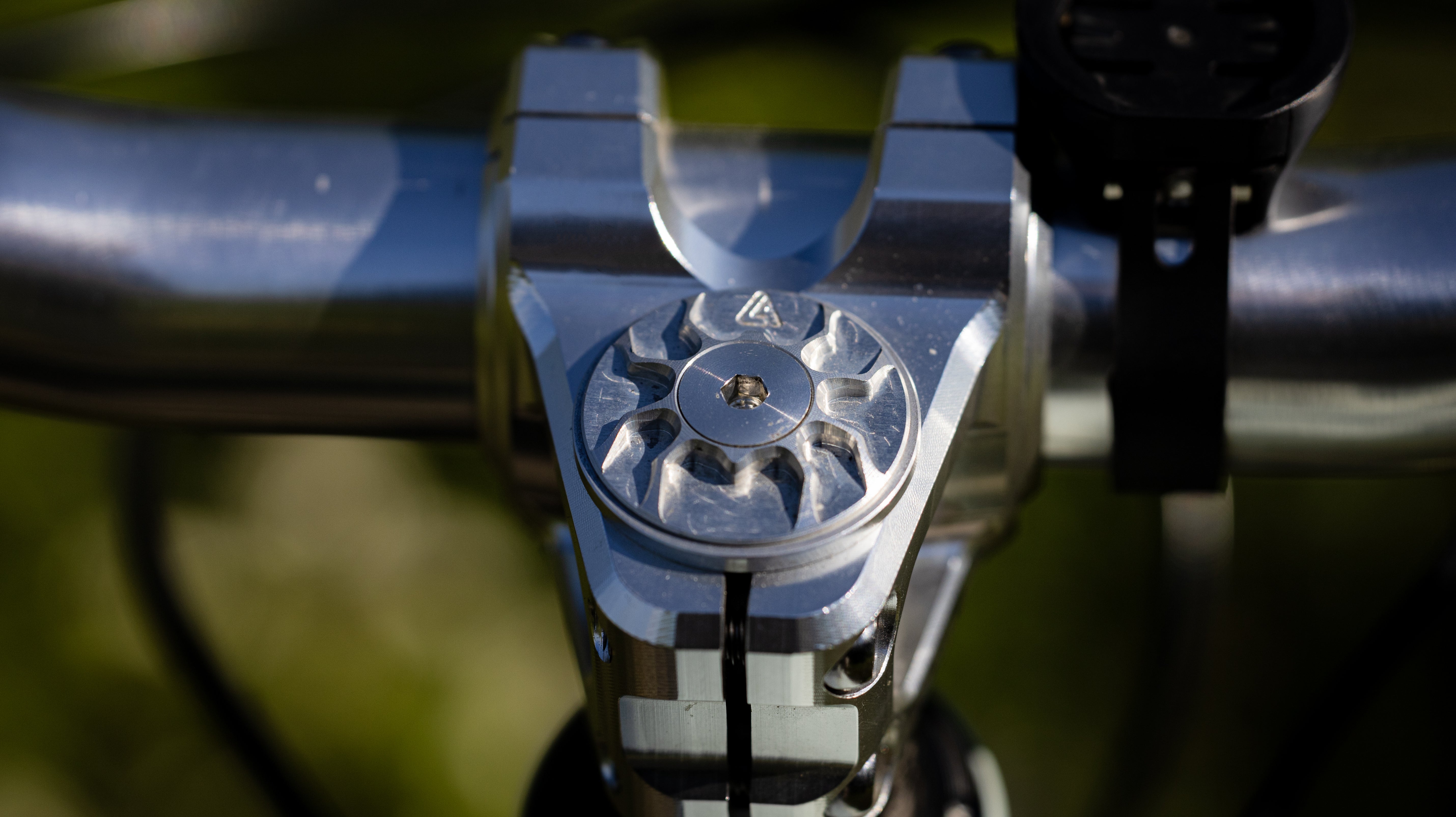 Silver machined ALUGEAR top cap with flower-cut face installed on stem, on-bike close-up