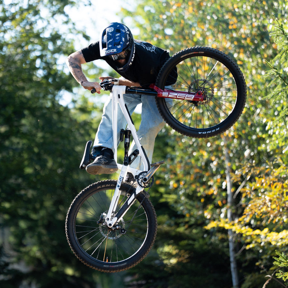 MTB rider jumping in forest on white bike equipped with titanium ALUGEAR Stellar Ti crankset