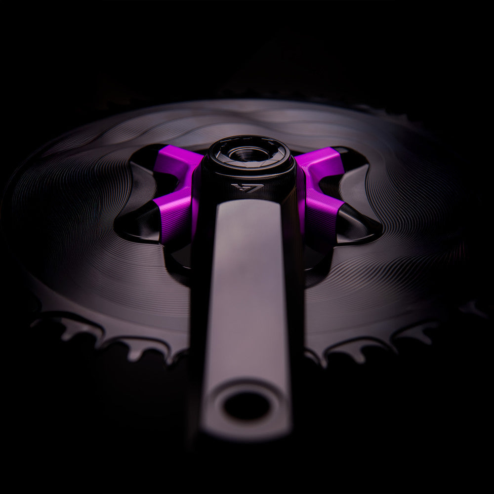 Purple anodized ALUGEAR 4-arm crank spider close-up with crank arm and road chainring, dark background